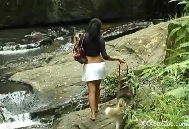 Stunning brunette fucks a dog by a waterfall
